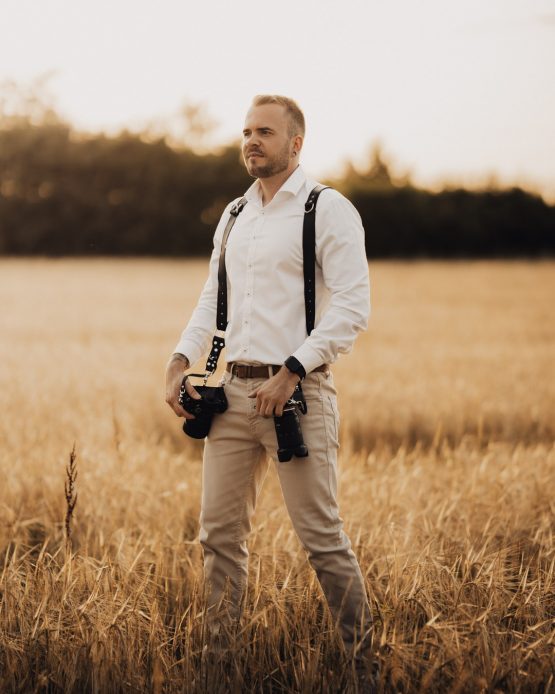 Der Hochzeitsfotograf Jan Klein steht auf einem Weizenfeld