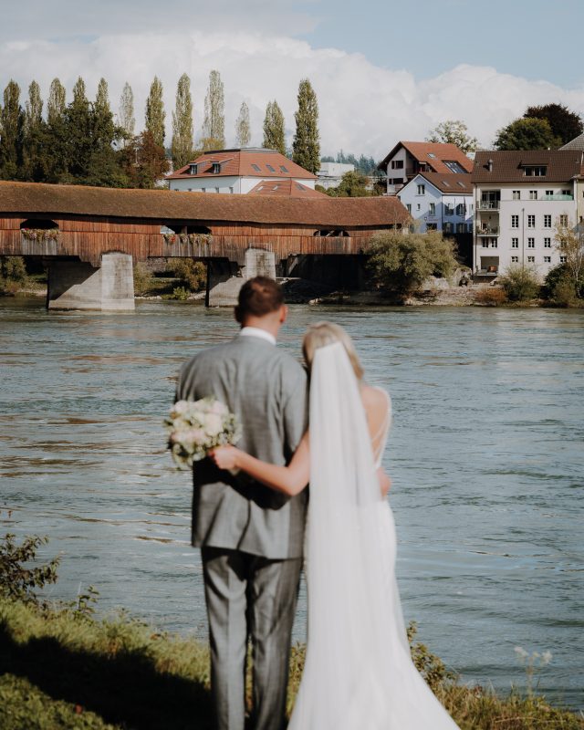 Das Brautpaar steht verliebt vor einem großen Fluss