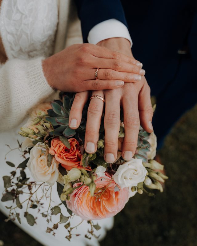 Ein Brautpaar zeigt ihre Hochzeitsringe.